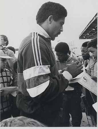 Daley Thompson signing autographs at the reopening of the Terence McMillan Stadium. 1985.