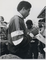 Daley Thompson signing autographs at the reopening of the Terence McMillan Stadium. 1985.